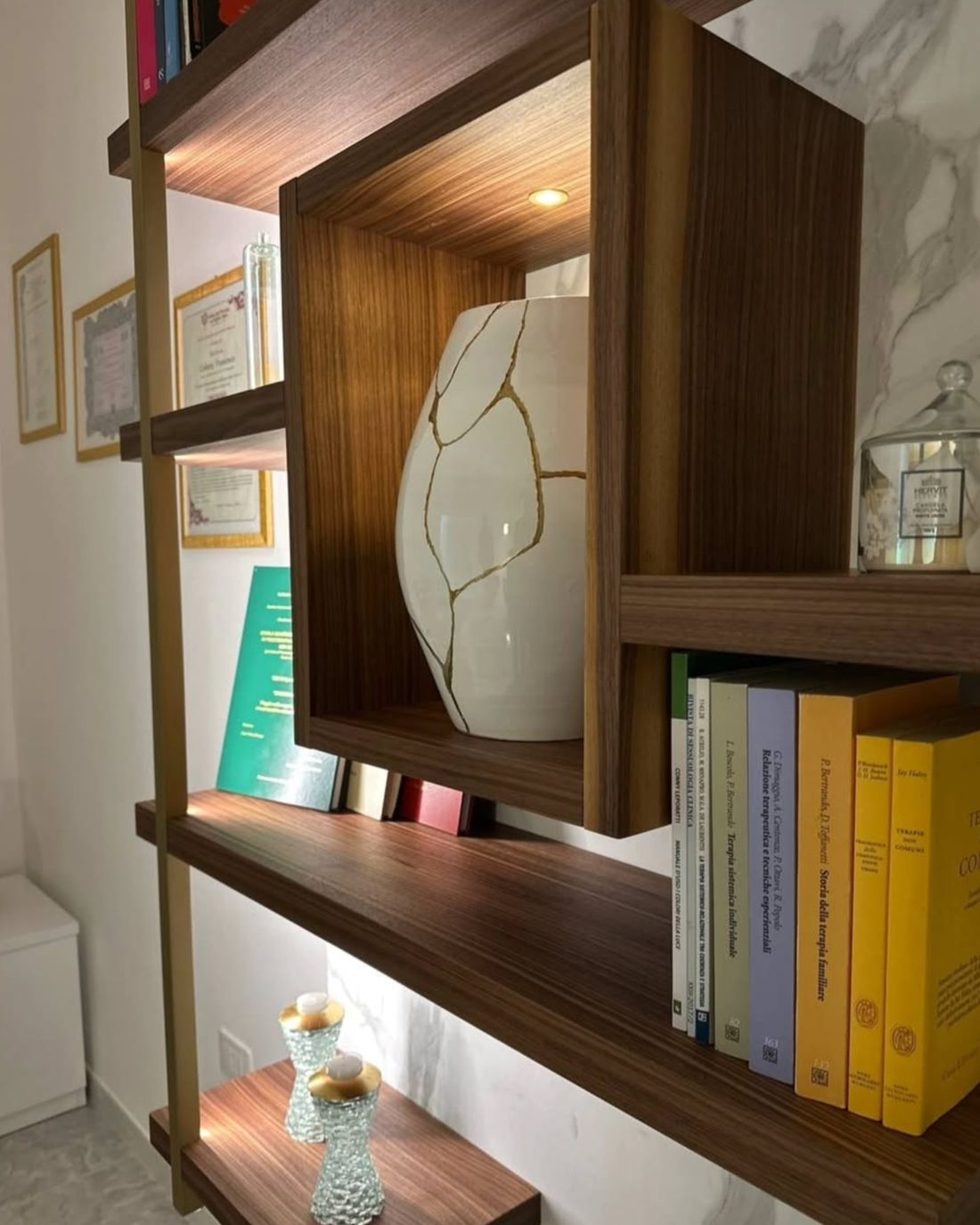 Un vaso bianco riparato con la tecnica del kintsugi nella libreria dello studio